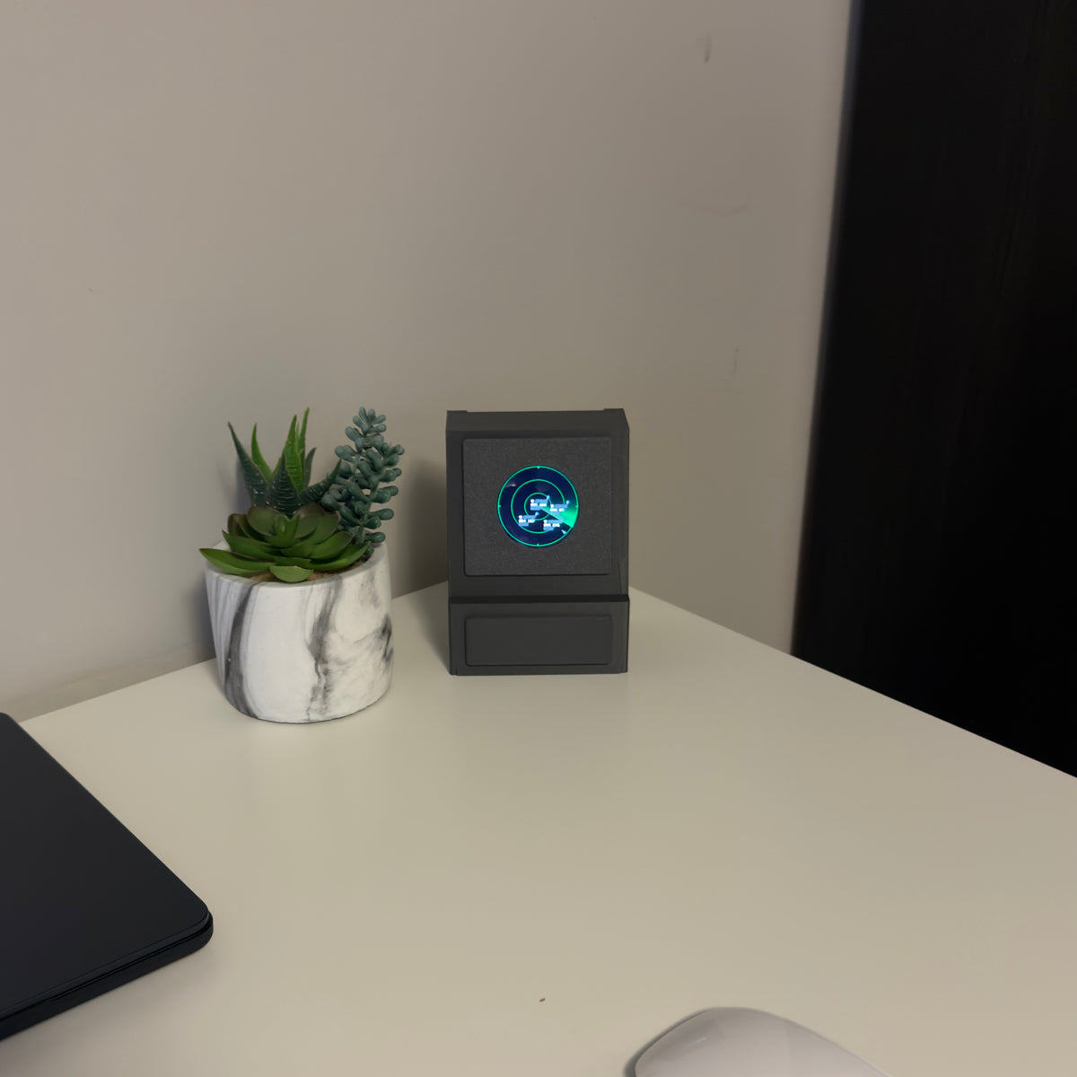 Gray DeskSpotter unit on a white desk next to a succulent planter