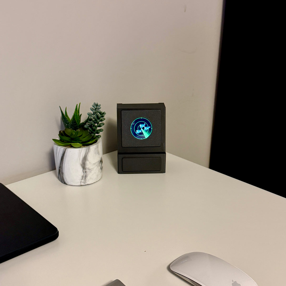 DeskSpotter on a desk beside a succulent, screen lit with the overhead aircraft view