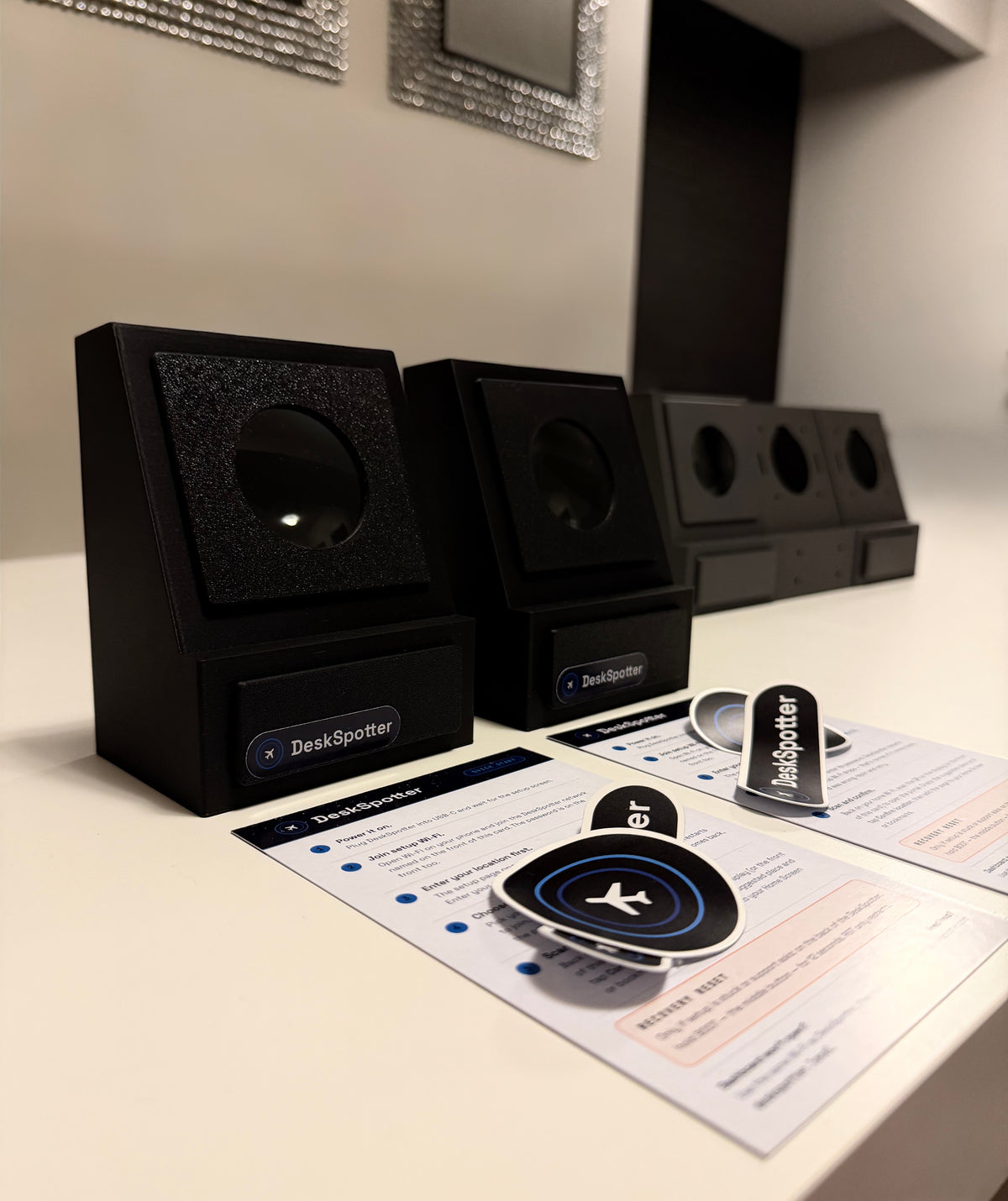 A small batch of DeskSpotter enclosures being hand-built, with quick-start cards and stickers